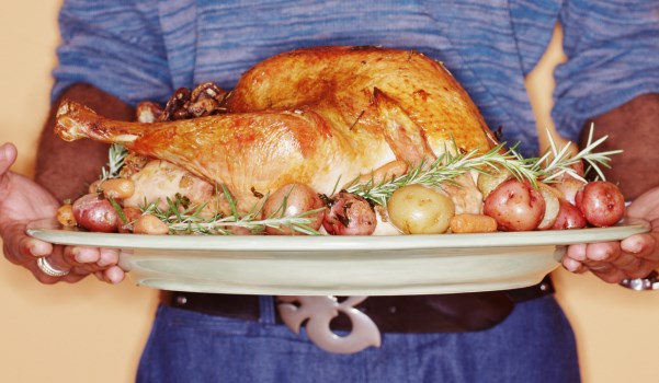 Young man holding roast turkey, mid section